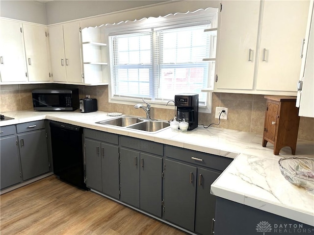 kitchen featuring gray cabinets, light wood-type flooring, sink, and black dishwasher