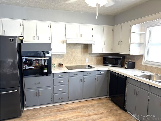 kitchen featuring gray cabinets, light hardwood / wood-style flooring, black appliances, and backsplash