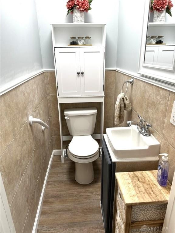 bathroom with sink, toilet, tile walls, and hardwood / wood-style flooring