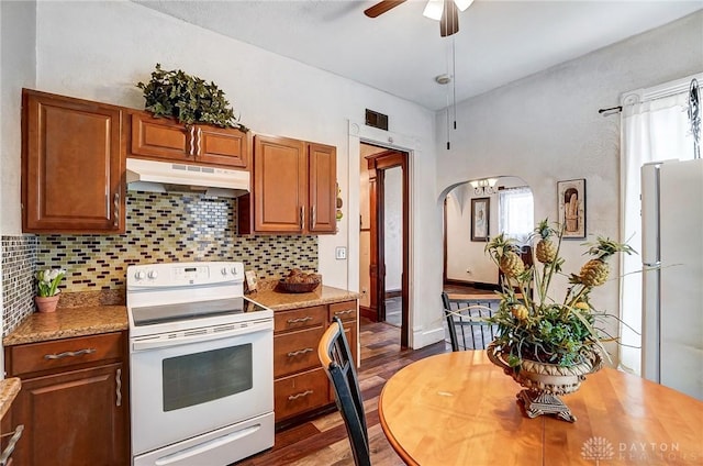 kitchen featuring dark wood-type flooring, refrigerator, decorative backsplash, a wealth of natural light, and electric stove