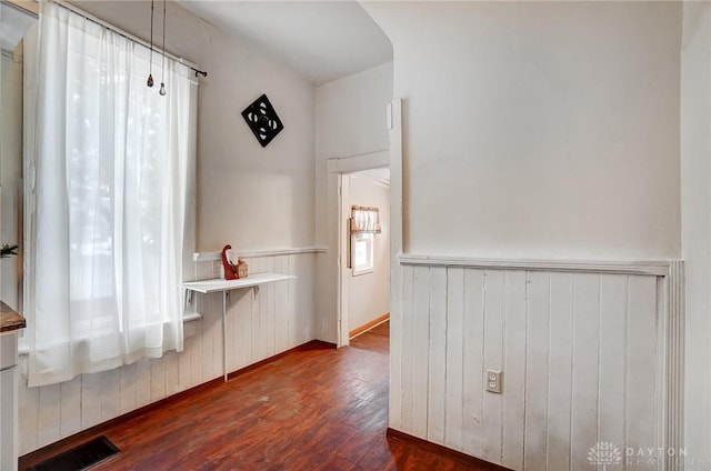 unfurnished dining area featuring dark wood-type flooring and wood walls