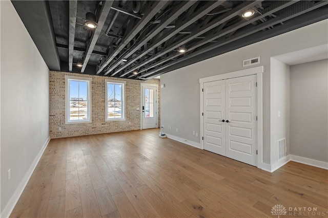 interior space featuring light hardwood / wood-style flooring and brick wall