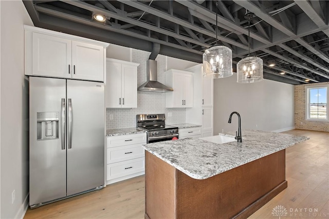 kitchen featuring white cabinetry, a kitchen island with sink, stainless steel appliances, wall chimney range hood, and pendant lighting