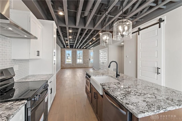 kitchen featuring a center island with sink, white cabinets, wall chimney range hood, and electric range oven