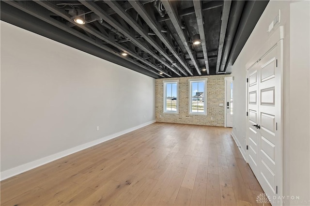 spare room with light hardwood / wood-style floors and brick wall