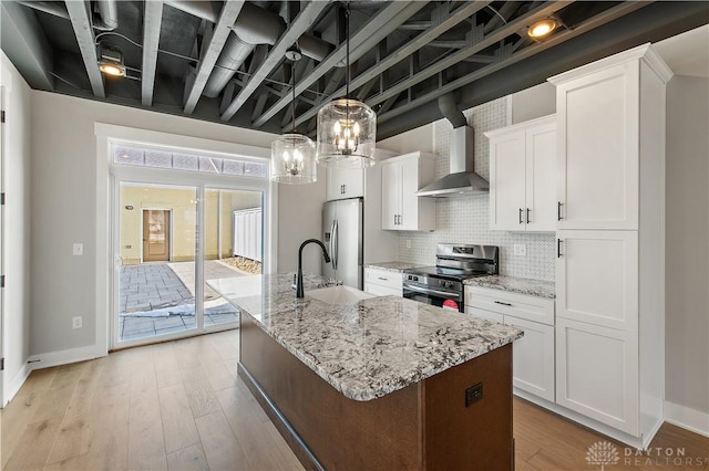 kitchen with an island with sink, wall chimney range hood, white cabinets, and stainless steel appliances