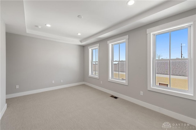 carpeted spare room featuring a tray ceiling