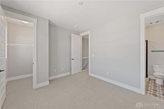 unfurnished bedroom featuring light carpet, a closet, and connected bathroom