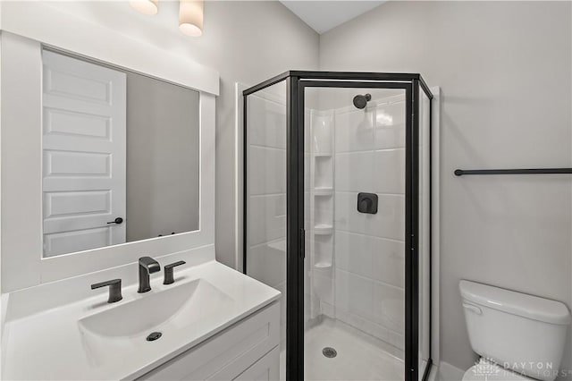 bathroom with toilet, vanity, and a shower with shower door