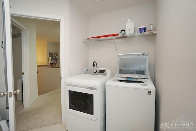 clothes washing area featuring washer and dryer and light carpet