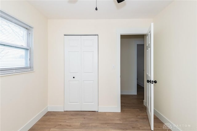 unfurnished bedroom featuring light wood-type flooring, a closet, and ceiling fan