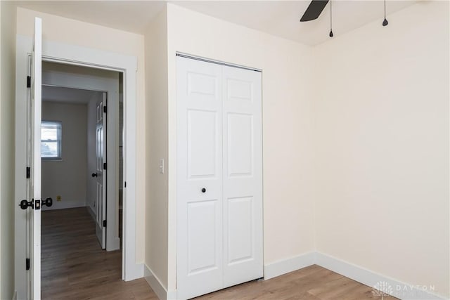 unfurnished bedroom featuring ceiling fan, light hardwood / wood-style flooring, and a closet