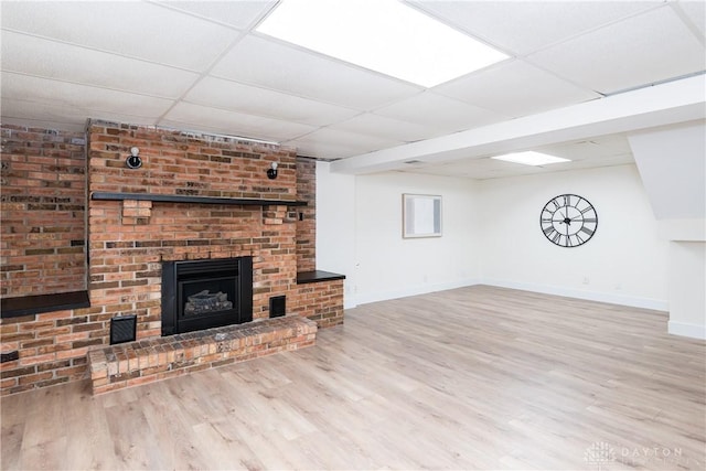 unfurnished living room featuring a paneled ceiling, hardwood / wood-style flooring, and a fireplace