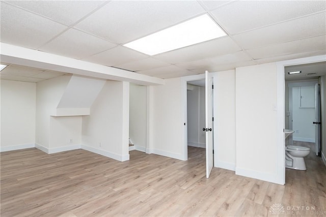 basement featuring light wood-type flooring and a drop ceiling