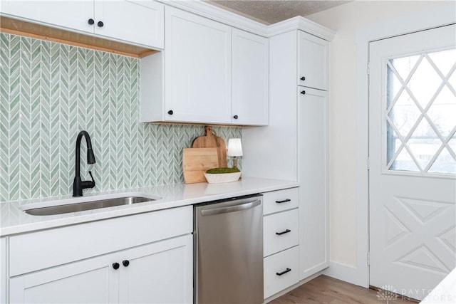 kitchen featuring white cabinetry, light hardwood / wood-style flooring, sink, stainless steel dishwasher, and tasteful backsplash