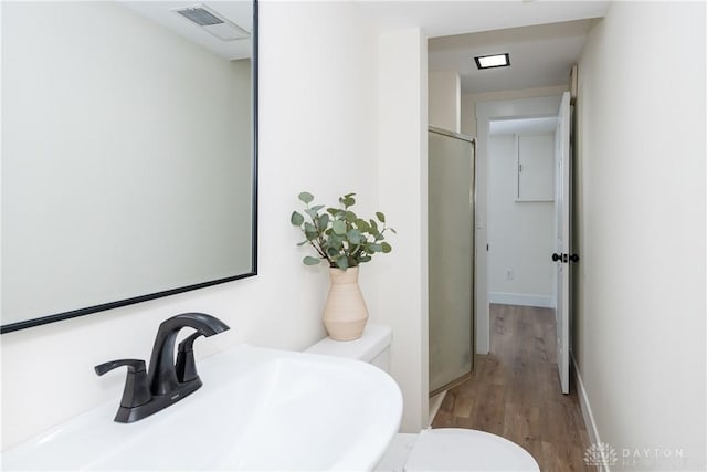 bathroom with hardwood / wood-style flooring, sink, a shower with shower door, and toilet