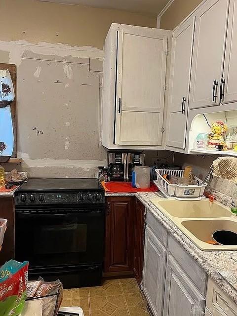 kitchen with light tile patterned flooring, sink, white cabinetry, and electric range