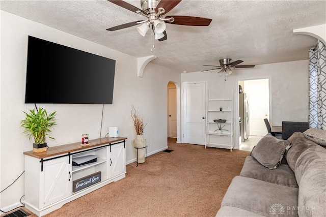 living room with ceiling fan, a textured ceiling, and light colored carpet