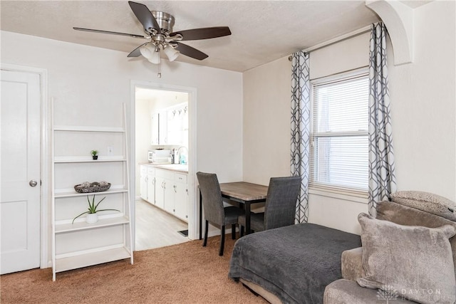 carpeted dining room with sink and ceiling fan