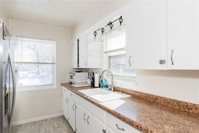 1908 John Glenn Rd, Dayton, OH 45420 - kitchen with open shelves, white cabinets, stainless steel fridge with ice dispenser, a sink, and light wood finished floors