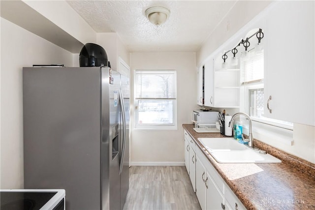 kitchen with light hardwood / wood-style flooring, stainless steel refrigerator with ice dispenser, sink, a textured ceiling, and white cabinets