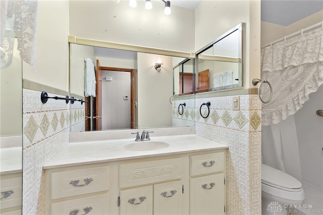 bathroom with tile walls, toilet, and vanity