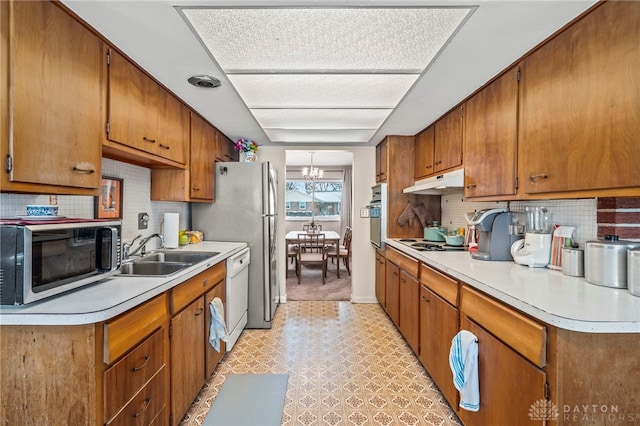 kitchen with sink, stainless steel appliances, an inviting chandelier, and backsplash