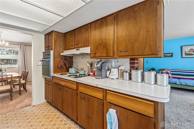 kitchen with an inviting chandelier, white electric cooktop, tasteful backsplash, oven, and light carpet