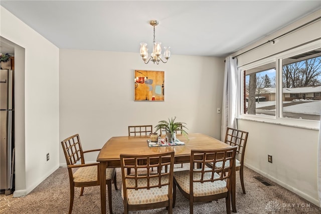 dining space with carpet flooring and an inviting chandelier