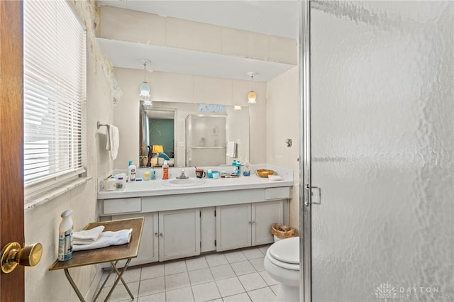 bathroom featuring tile patterned flooring, vanity, toilet, and a shower with shower door