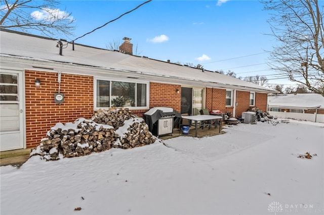 snow covered rear of property with central AC unit