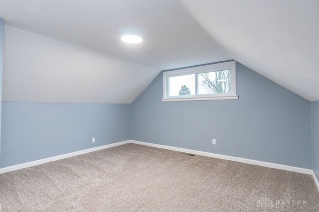 bonus room with vaulted ceiling and carpet flooring