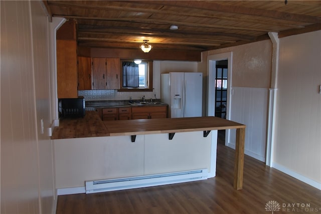 kitchen featuring a kitchen bar, white fridge with ice dispenser, a baseboard radiator, wooden ceiling, and kitchen peninsula