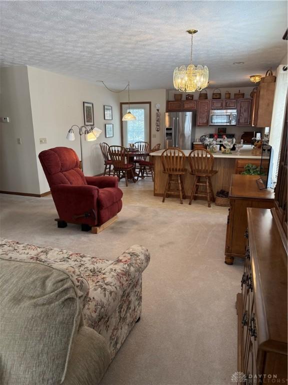 carpeted living room with a textured ceiling and a notable chandelier