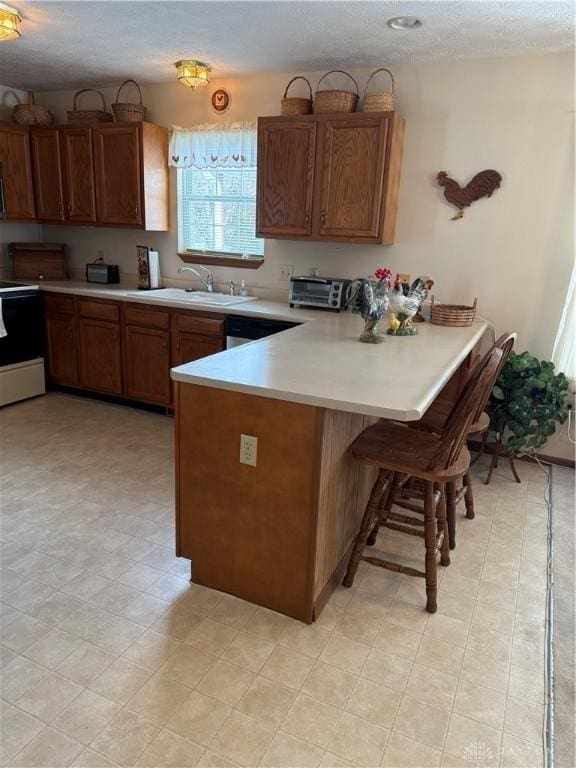 kitchen with a kitchen breakfast bar, sink, range with electric cooktop, and kitchen peninsula