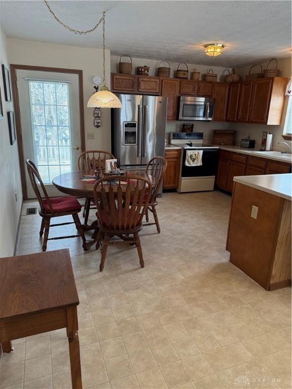 kitchen featuring decorative light fixtures, sink, stainless steel appliances, and a textured ceiling