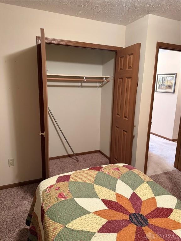 carpeted bedroom with a textured ceiling and a closet