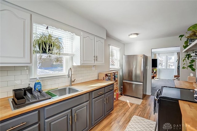 kitchen featuring gray cabinetry, white cabinetry, black electric range oven, and stainless steel fridge