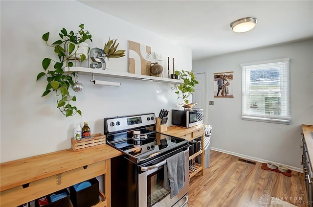 kitchen featuring appliances with stainless steel finishes, light hardwood / wood-style flooring, and wooden counters