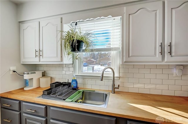 kitchen with white cabinetry, tasteful backsplash, and wood counters