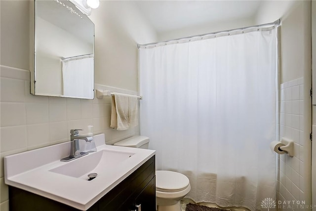 bathroom featuring toilet, tile walls, curtained shower, and vanity