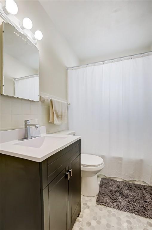 bathroom featuring vanity, tasteful backsplash, toilet, and walk in shower