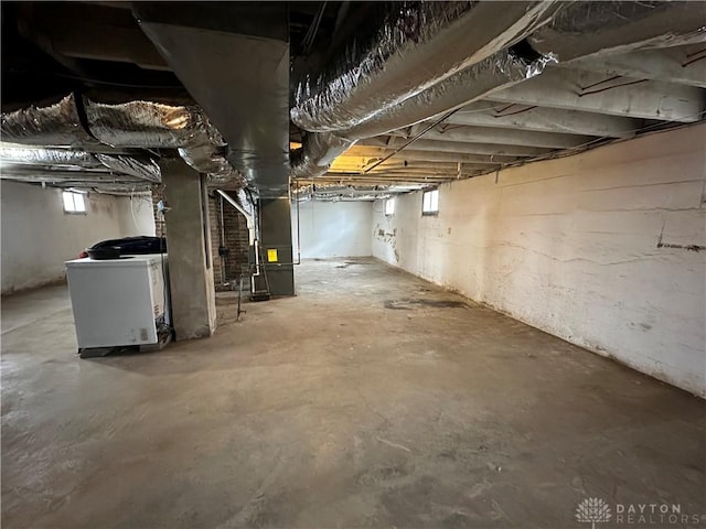 basement featuring plenty of natural light, heating unit, and washer / dryer