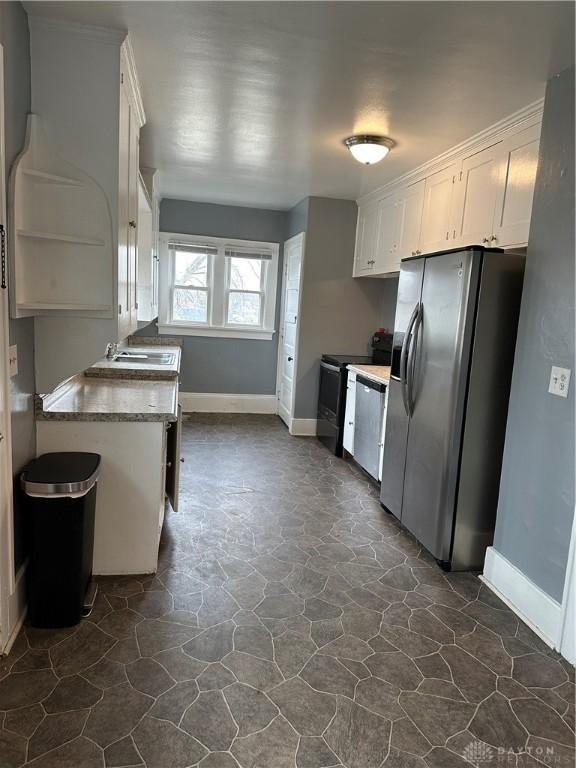 kitchen with appliances with stainless steel finishes, white cabinetry, and light stone counters