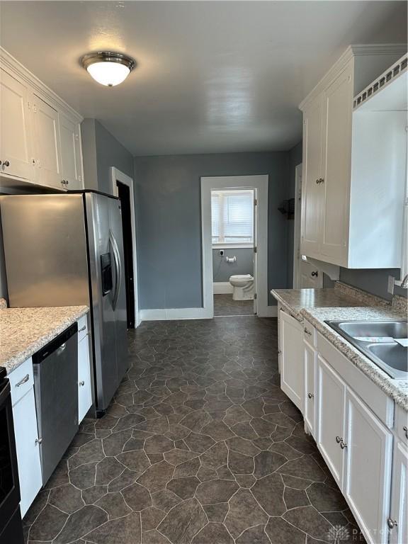 kitchen with white cabinetry, sink, light stone countertops, and stainless steel dishwasher