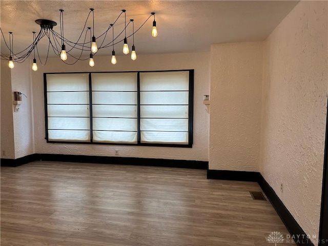 spare room featuring hardwood / wood-style flooring and an inviting chandelier