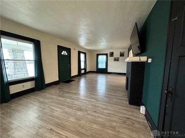 foyer entrance with a textured ceiling, a fireplace, and light hardwood / wood-style flooring