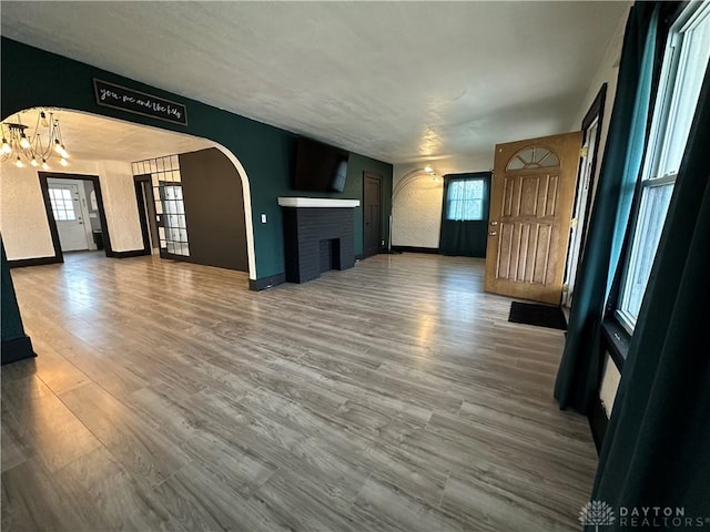 unfurnished living room with hardwood / wood-style flooring, an inviting chandelier, and a fireplace