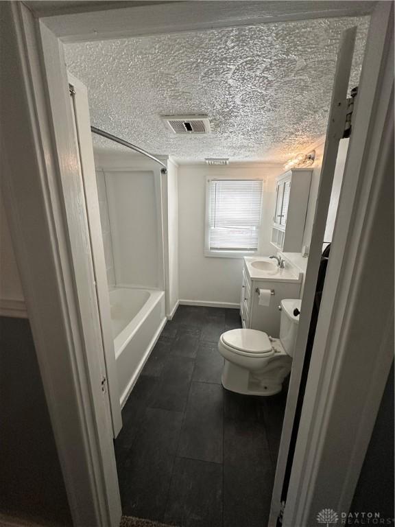 bathroom with tile patterned floors, a textured ceiling, vanity, and toilet