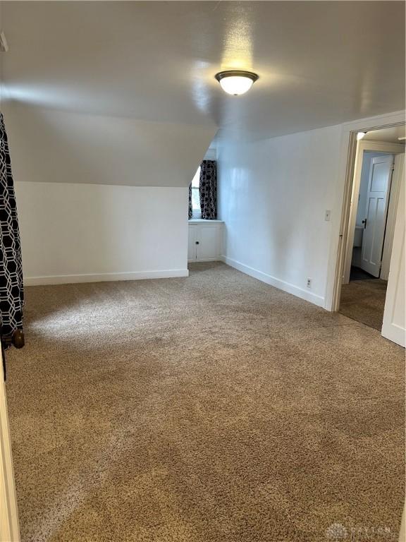 additional living space with vaulted ceiling and carpet floors